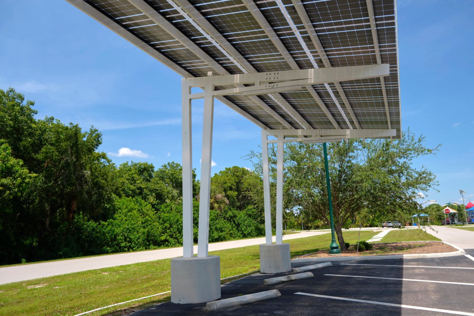 Solar panel canopy shading parking stalls beside trees and a landscaped island