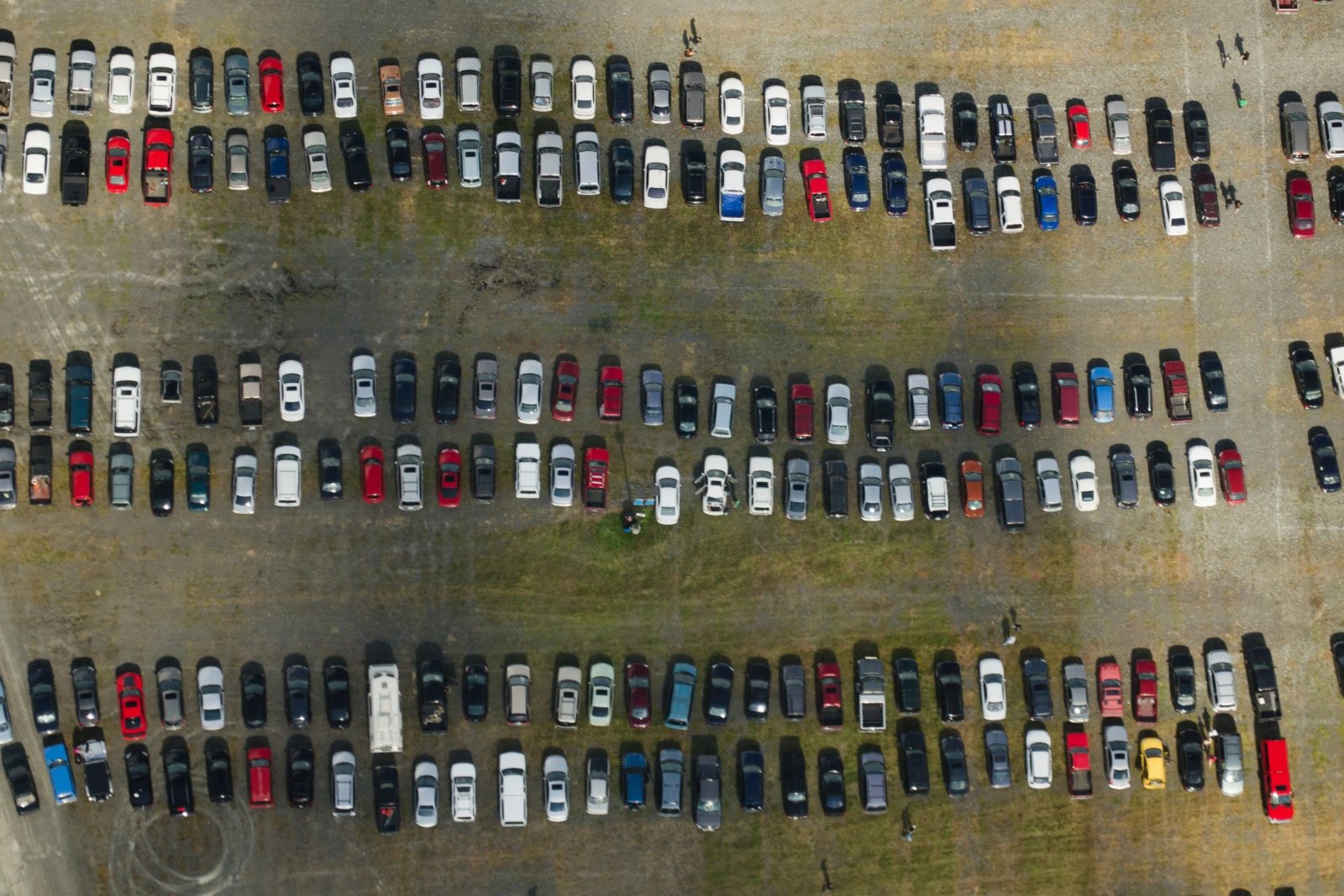 Overhead view of rows of parked cars filling a large unpaved surface lot