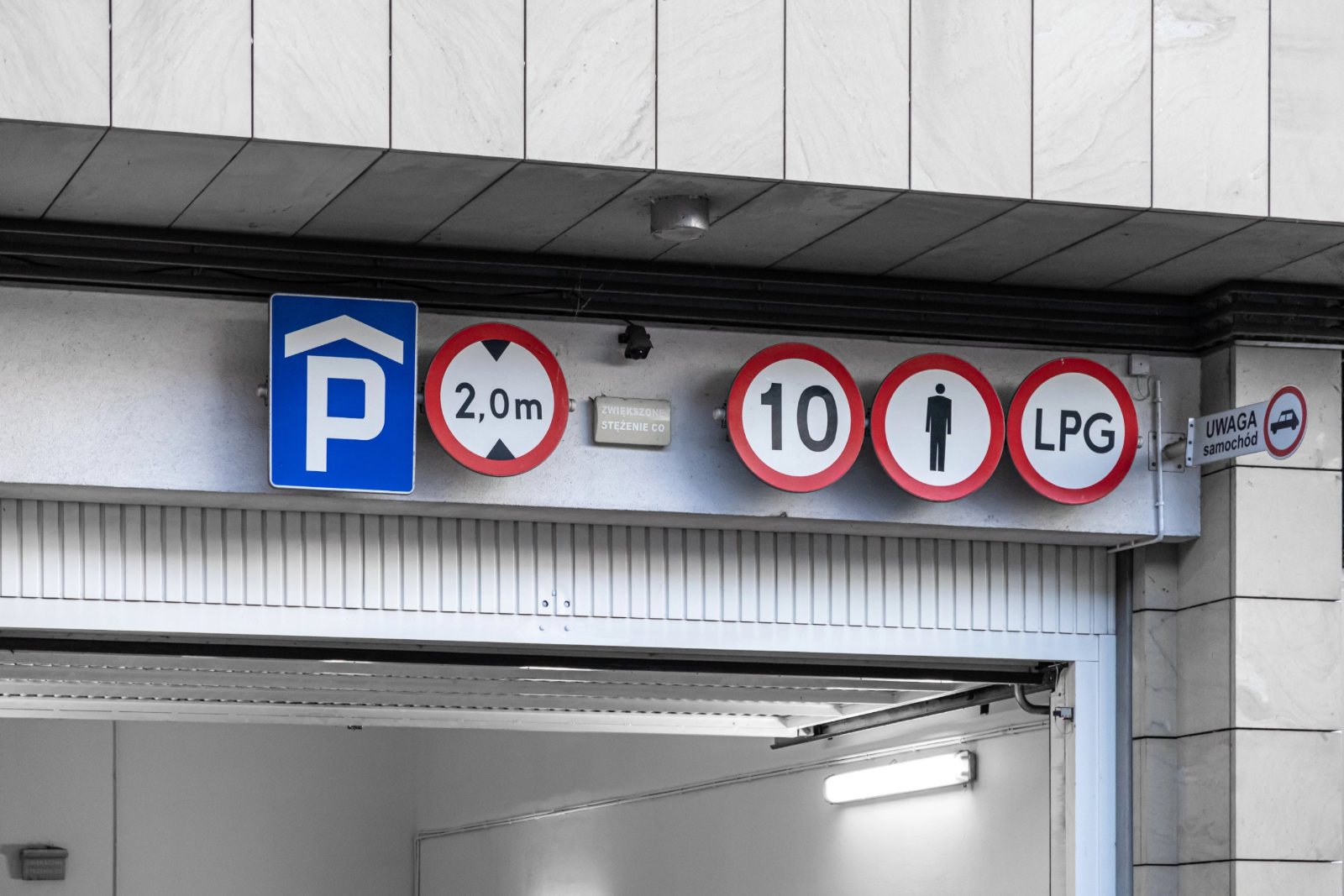 Underground garage entrance with a row of parking, height, speed, pedestrian and LPG signs